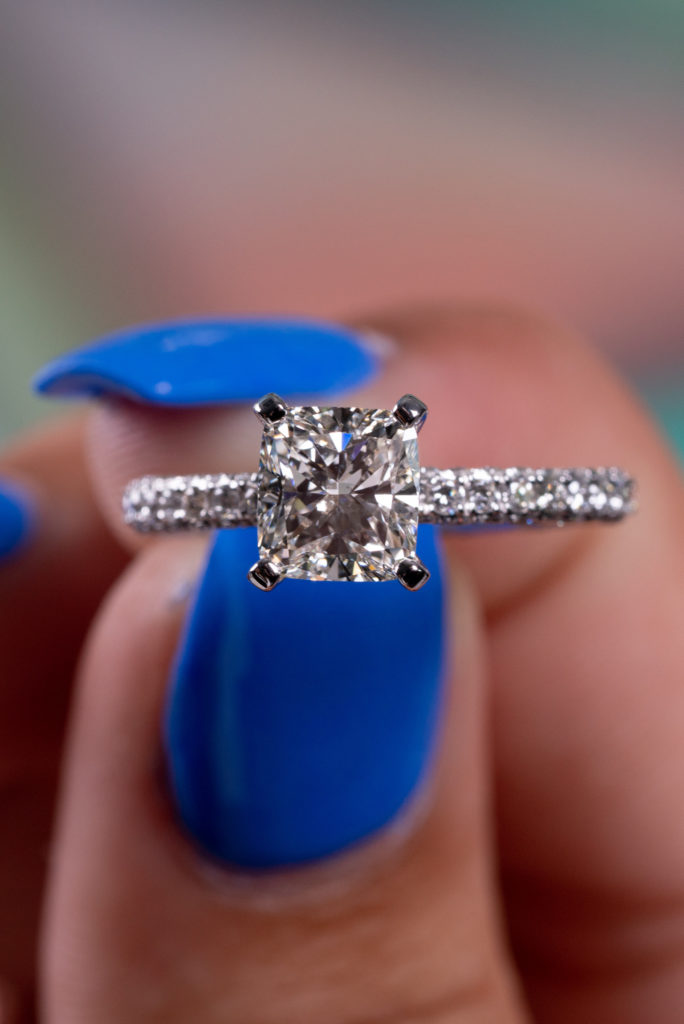 close view of a colorless cushion cut ring with accents