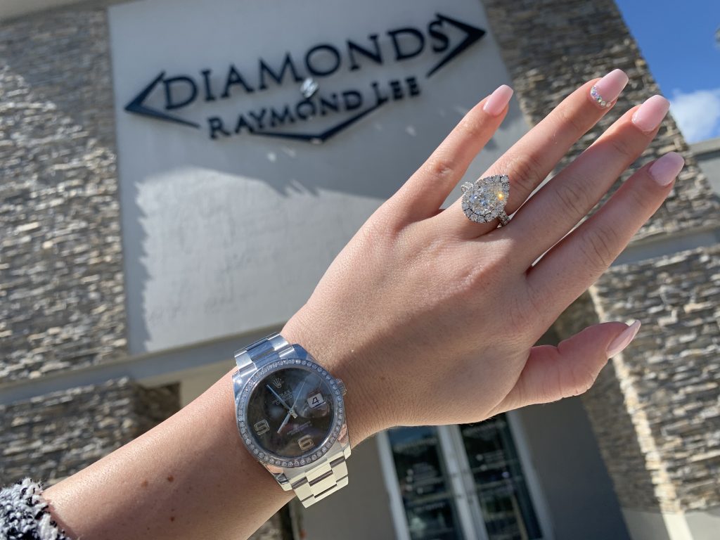 used rolex datejust worn with halo engagement ring in front of local watch store diamonds by raymond lee